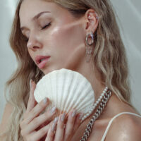 Donna con inserto piercing e conchiglia, orecchini in argento e oro