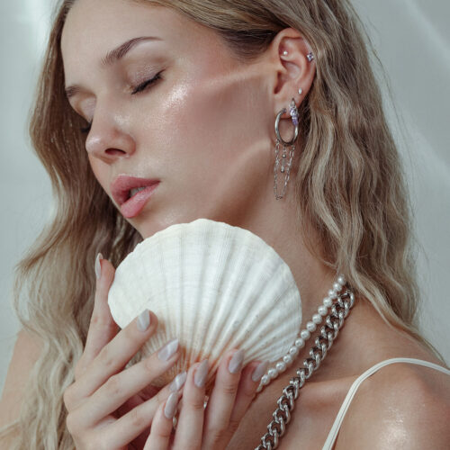 Donna con inserto piercing e conchiglia, orecchini in argento e oro