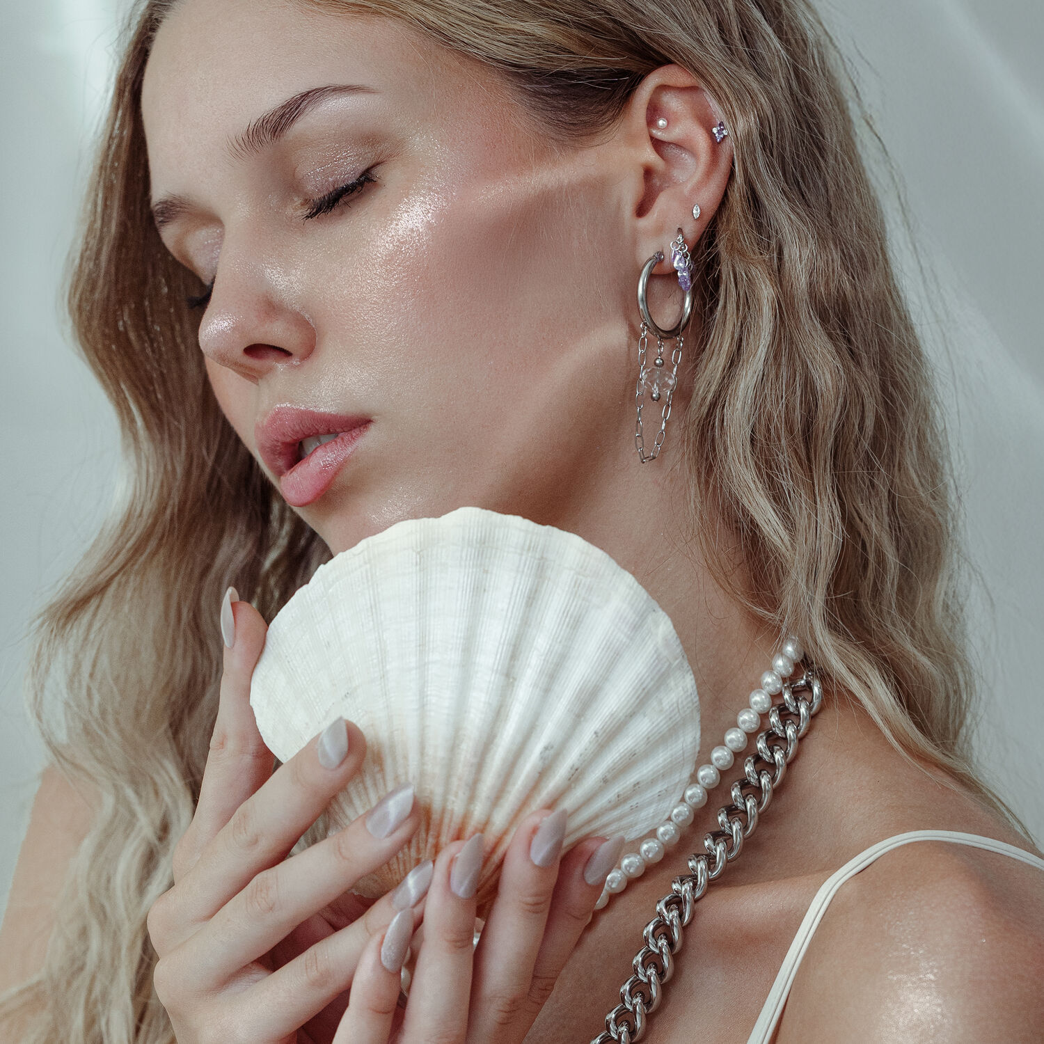 Donna con inserto piercing e conchiglia, orecchini in argento e oro