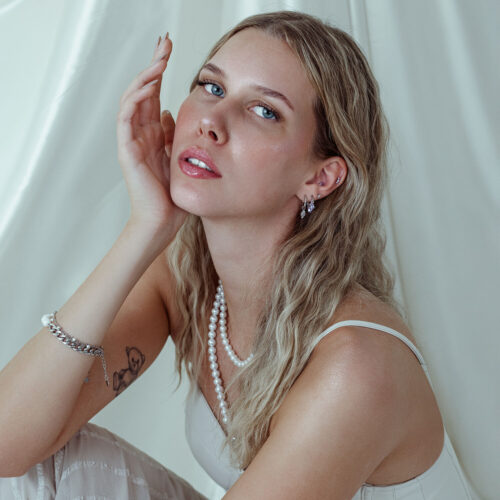 Donna con cristallo Push Fit in lavanda all'orecchio su sfondo bianco