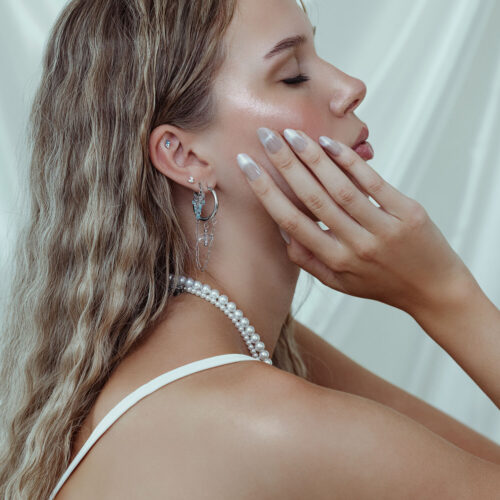 Primo piano di un orecchino con attacco Crystal Reef in lavanda e turchese su un orecchio