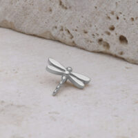 Inserto a forma di libellula in titanio argentato su sfondo di pietra chiara