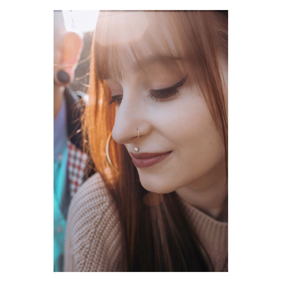 Donna con capelli castani indossa un Septum Clicker dorato con design a corda intrecciata