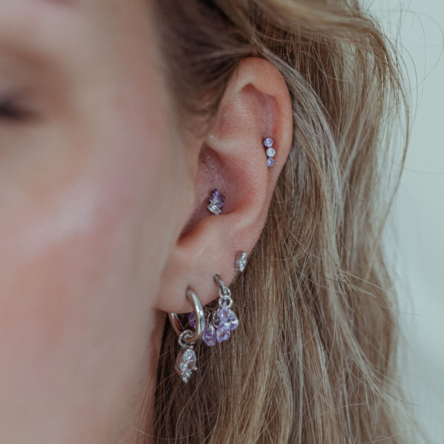 Orecchio con accessorio piercing in lavanda e metallo argentato, primo piano