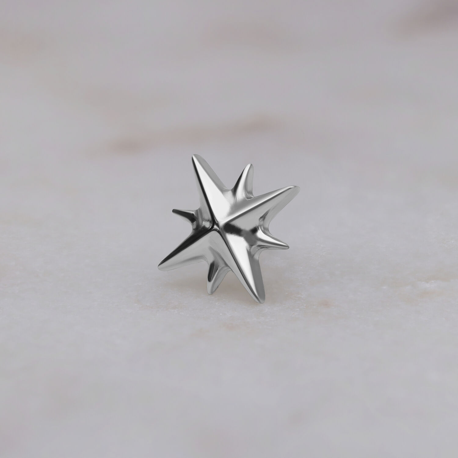 Silberner sternförmiger Aufsatz aus Titan auf hellem Hintergrund