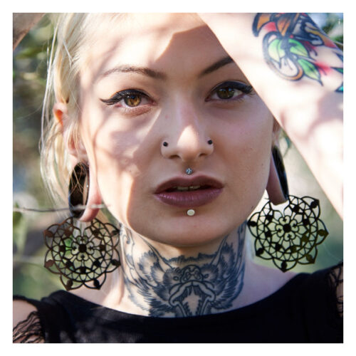 Donna con grandi orecchini floreali neri in acciaio chirurgico