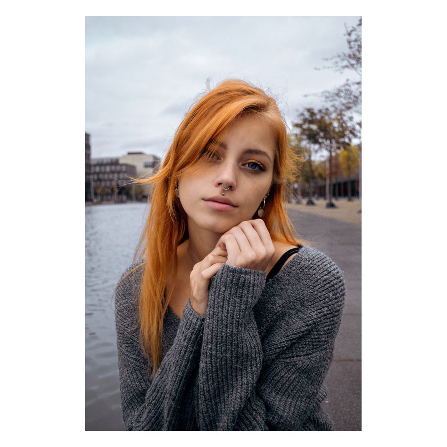 Giovane donna con piercing al naso e maglione grigio su sfondo urbano