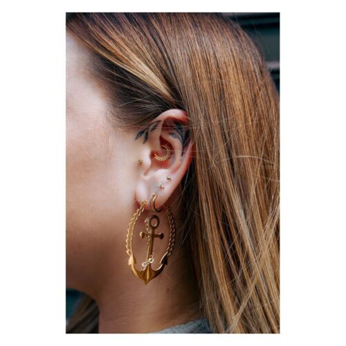 Donna con piercing dorati nell'orecchio, incluso un Little Balls Crystal Clicker