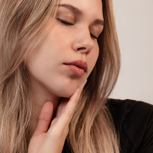 Donna con occhio chiuso, indossa un elegante piercing al naso in titanio nero