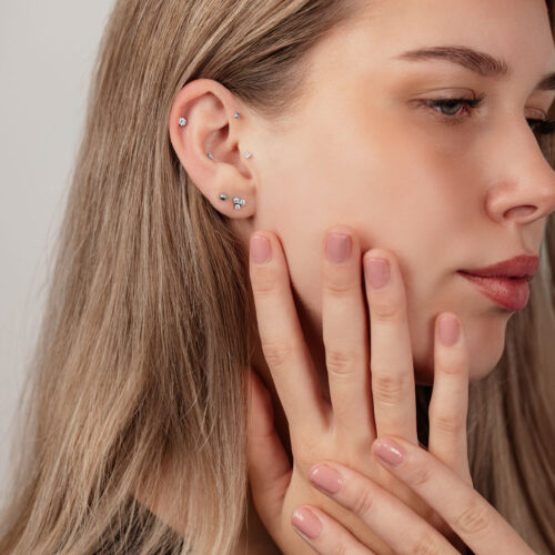 Primo piano di un orecchio con sfere labret in titanio argentato di varie dimensioni