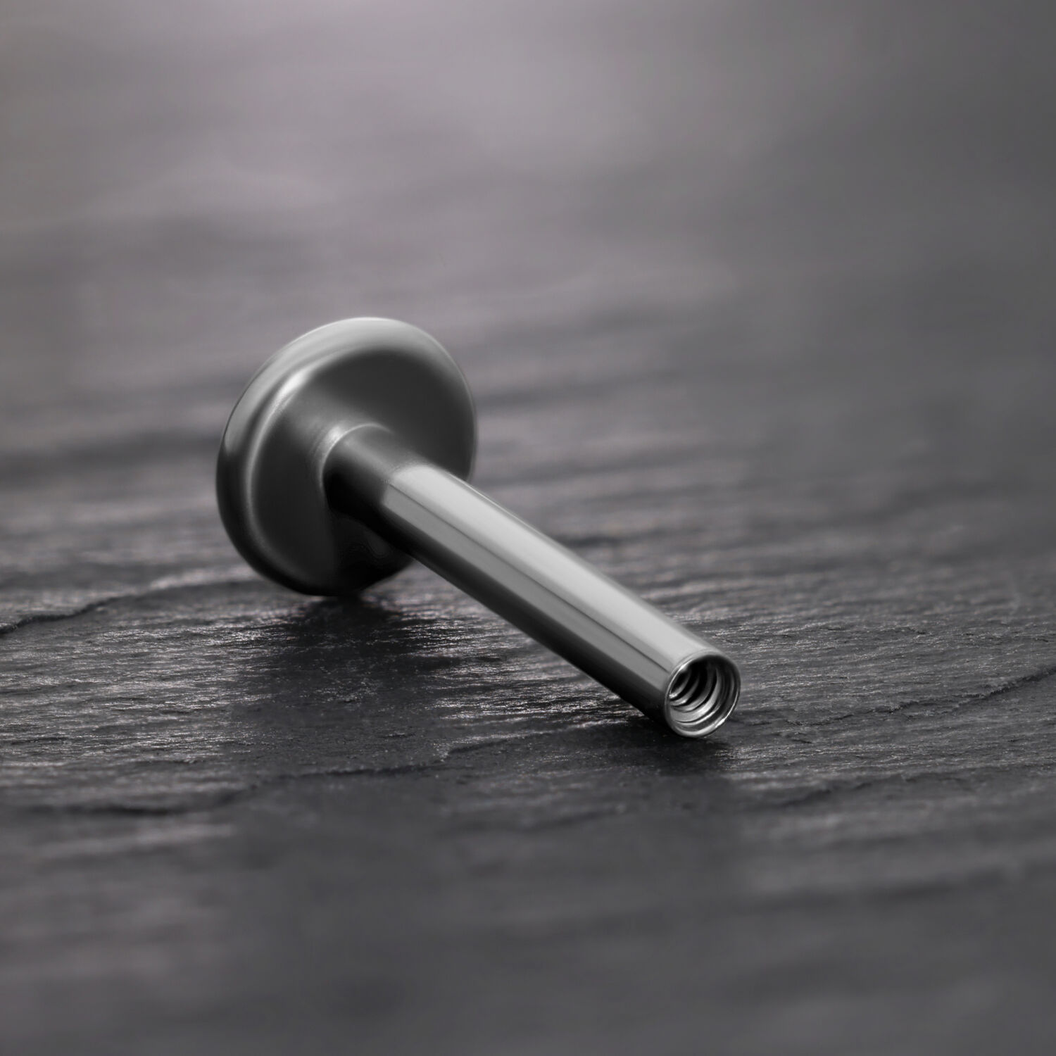 Barra Labret in titanio nero con filettatura interna su sfondo nero