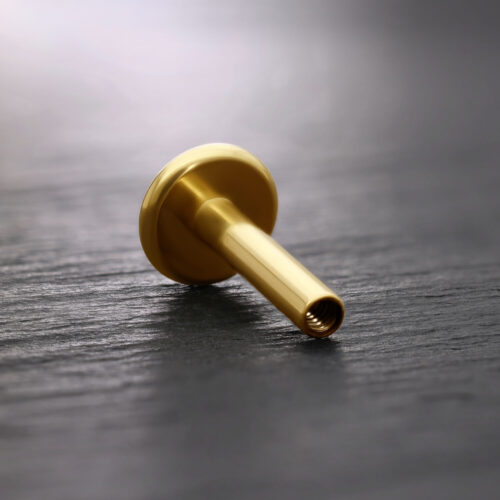 Labret in titanio dorato su sfondo scuro, inclinato