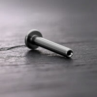 Labret Push Fit in titanio argento su sfondo di legno scuro