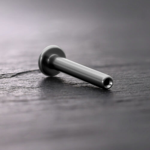 Labret Push Fit in titanio argento su sfondo di legno scuro