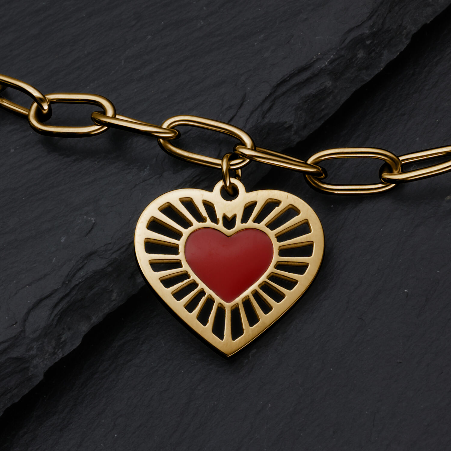 Bracciale in metallo dorato con ciondolo a forma di cuore e cuore rosso su sfondo ardesia