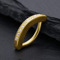 Clicker dorato per ombelico con cristalli di moissanite su sfondo nero