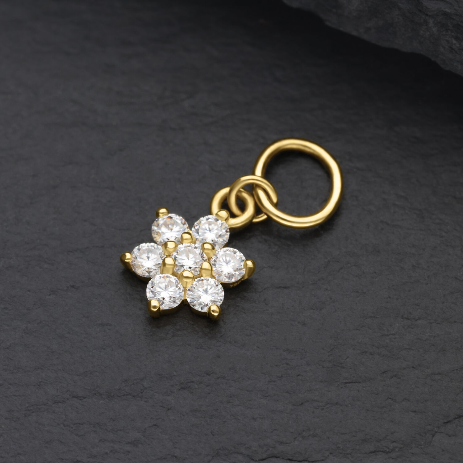 Pendente a fiore dorato in oro 18K con cristalli di moissanite chiari su sfondo nero