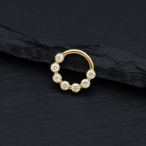 Anello piercing dorato con pietre di moissanite scintillanti su sfondo nero