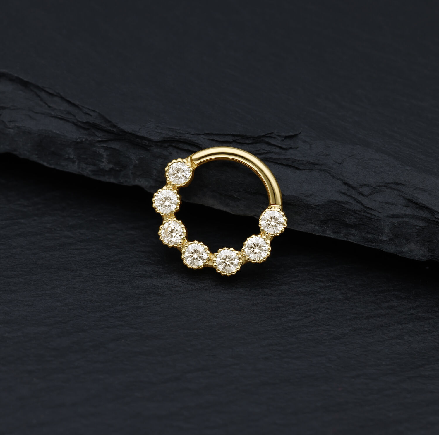 Anello piercing dorato con pietre di moissanite scintillanti su sfondo nero