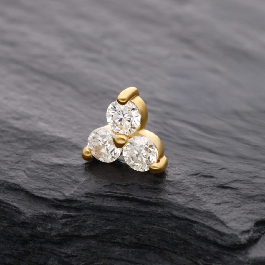 Attacco in oro 14K con tre pietre di moissanite su sfondo nero