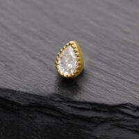 Attacco in moissanite dorato a forma di goccia su sfondo grigio