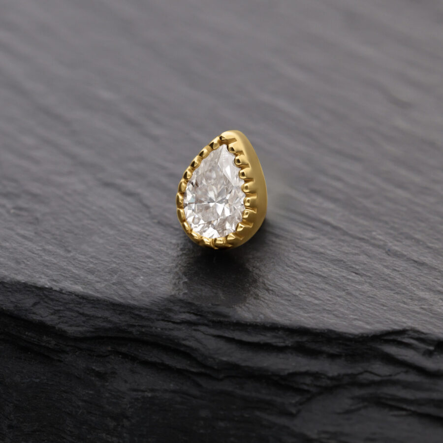 Attacco in moissanite dorato a forma di goccia su sfondo grigio