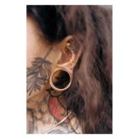 Bananabell Piercing in oro rosa nell'orecchio con tatuaggio sullo sfondo