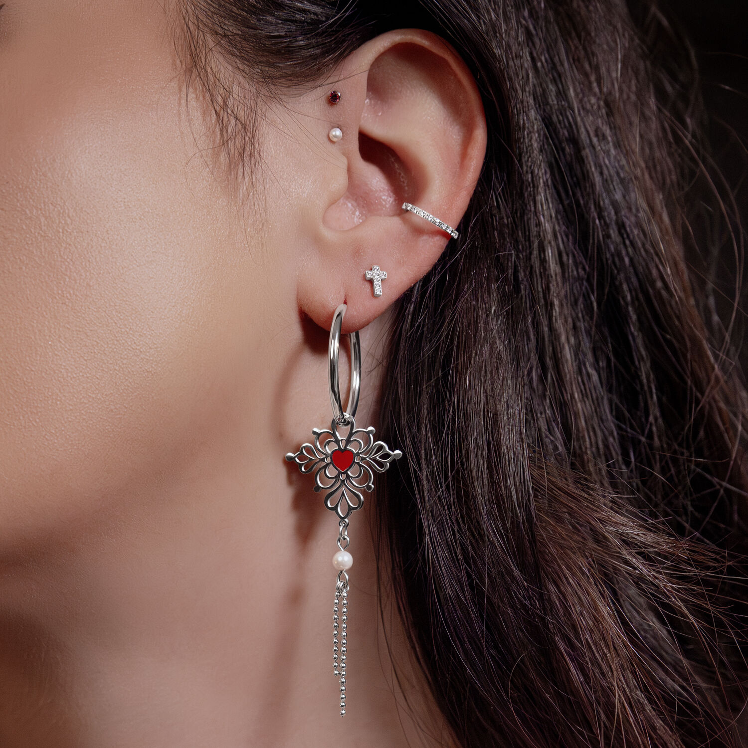 Donna con orecchini, cerchi argento con ciondolo a cuore rosso e catene, piercing all'orecchio