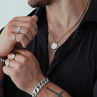 Collana unisex in acciaio chirurgico, indossata da una persona con camicia nera