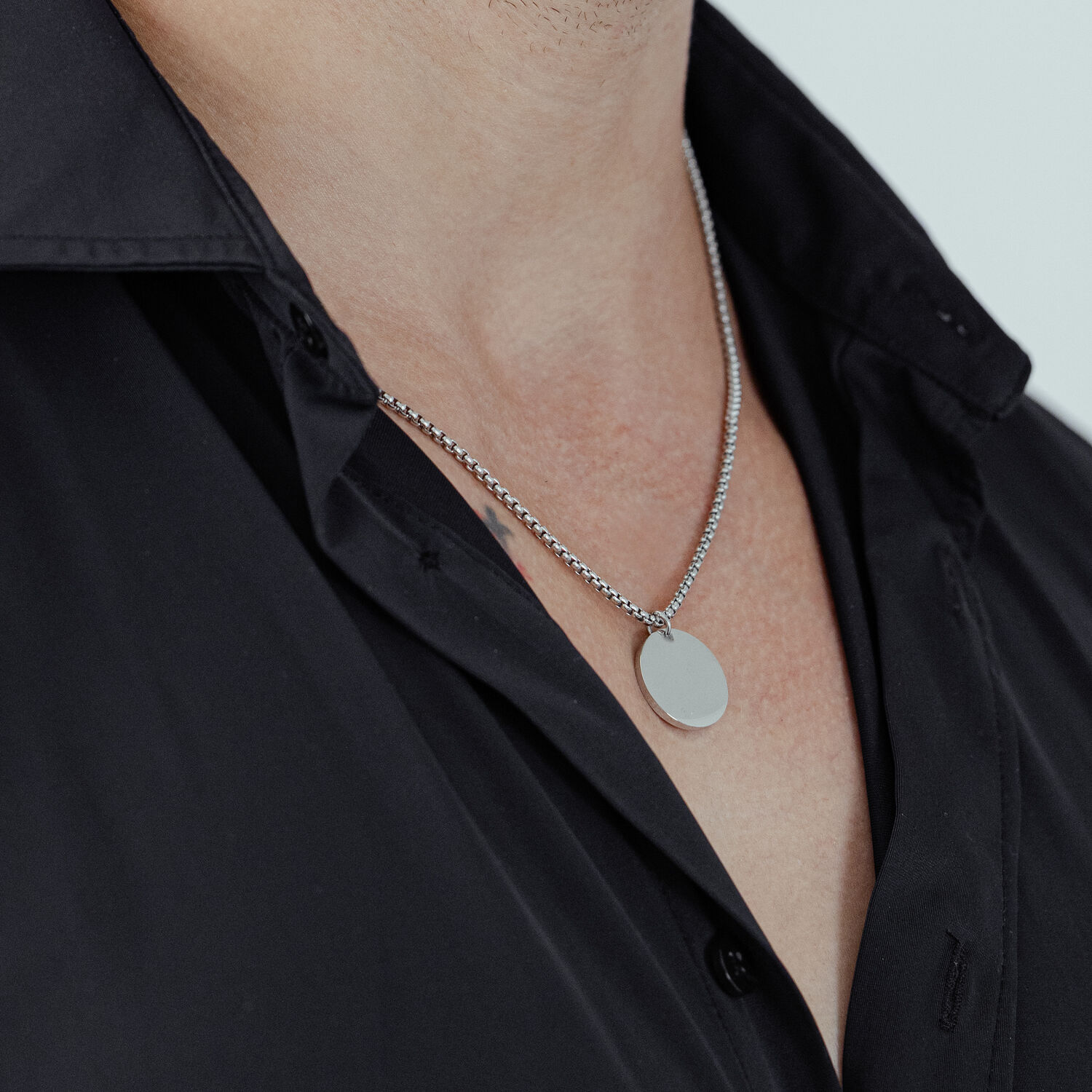 Collana d'argento con ciondolo rotondo su una camicia nera