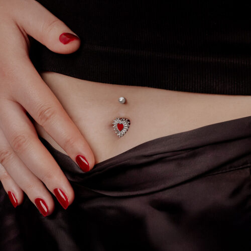 Donna con smalto rosso mostra Sacred Heart Bananabell nell'ombelico