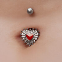 Piercing all'ombelico con design a cuore rosso e accenti argentati sulla pelle