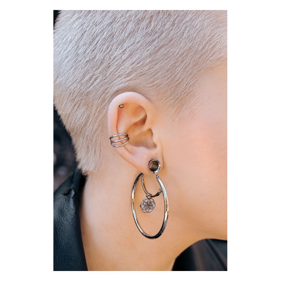 Orecchio con piercing a tunnel in argento e orecchino vistoso, capelli corti