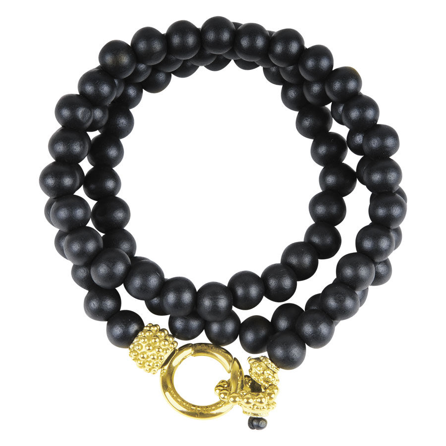 Braccialetto nero con perle di legno e chiusura dorata su sfondo bianco