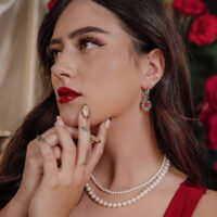 Donna con orecchini Sacred Heart in argento e collana di perle, sfondo con rose rosse
