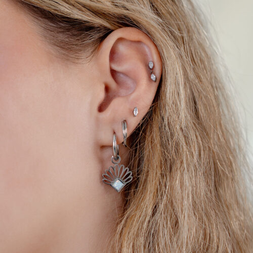 Orecchini d'argento con design a ventaglio di opale indossati su un orecchio