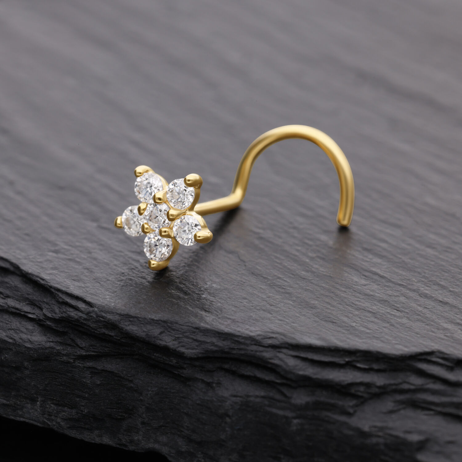Piercing al naso in oro con cristallo di moissanite a forma di fiore su sfondo scuro