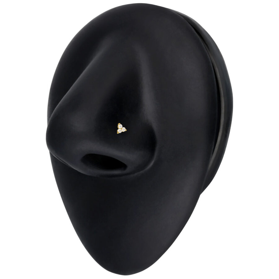 Piercing al naso in oro con tre cristalli chiari su sfondo nero