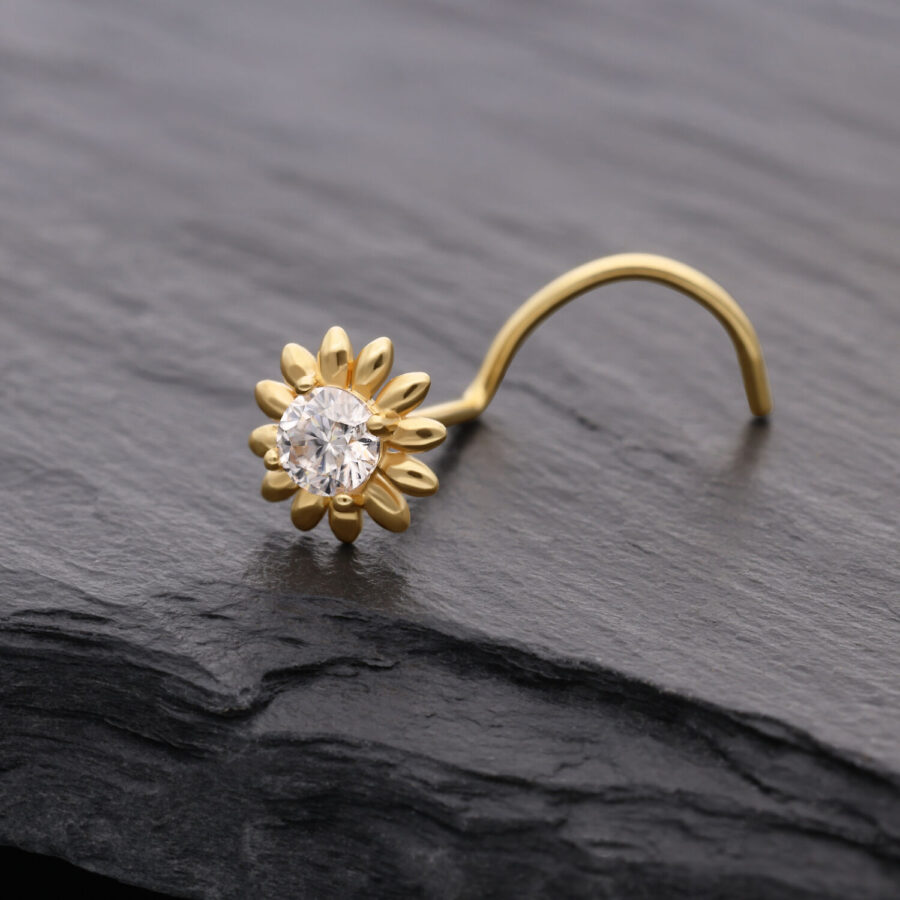 Piercing al naso dorato a forma di girasole con cristallo chiaro su sfondo scuro