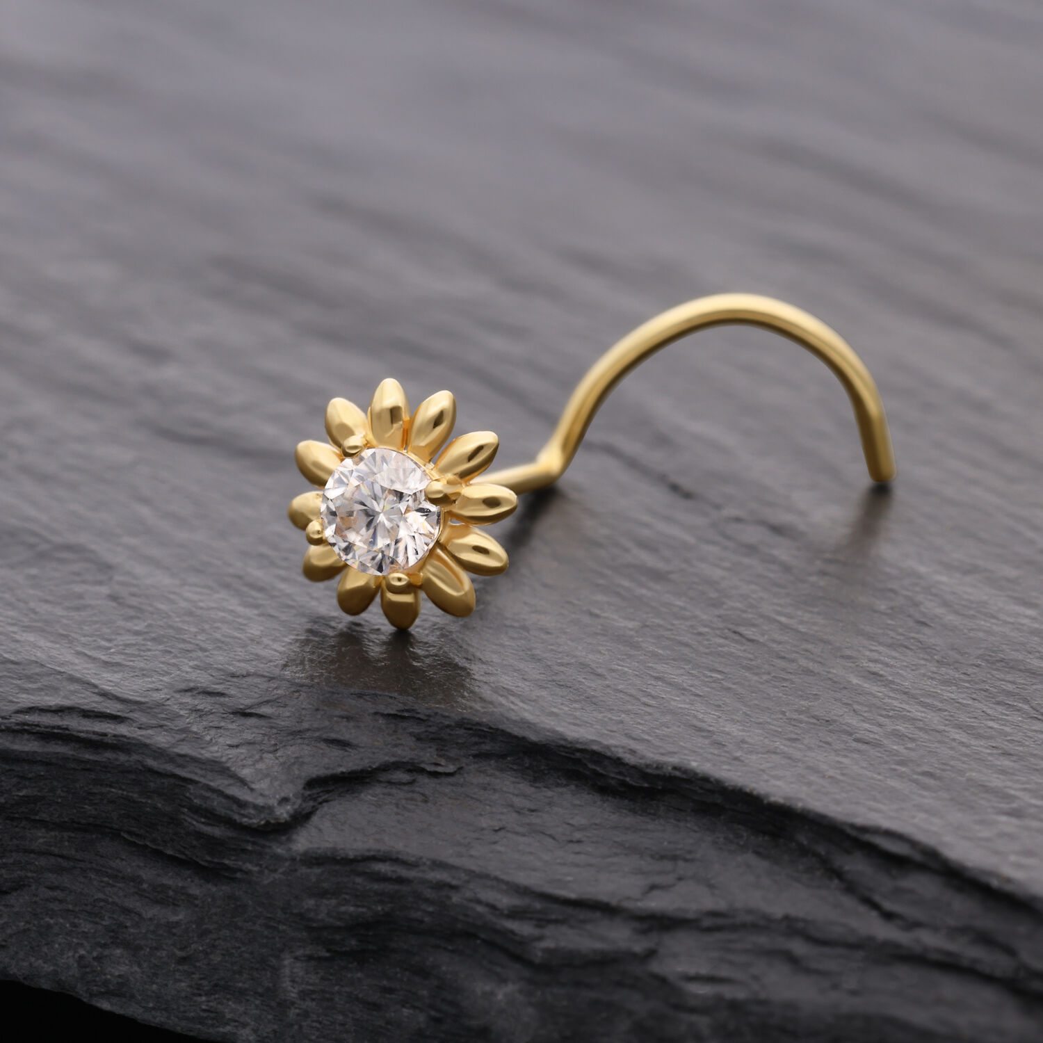 Piercing al naso dorato a forma di girasole con cristallo chiaro su sfondo scuro