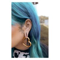 Piercing Bananabell dorato nell'orecchio con capelli blu e orecchino a cuore.