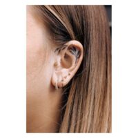 Primo piano di un orecchio con diversi piercing in oro, incluso l'Euphoria Clicker.