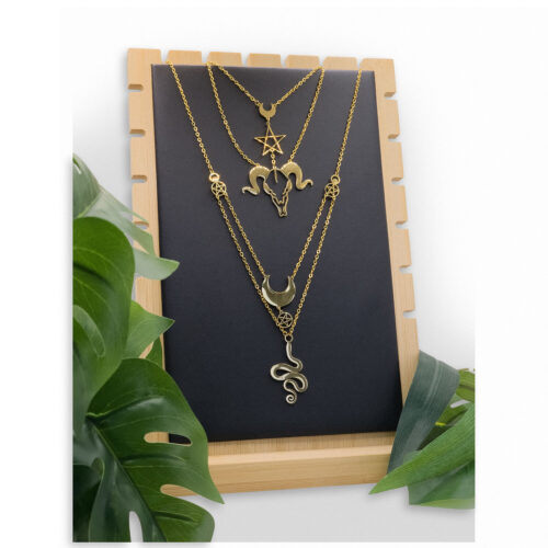 Espositore nero con tre collane dorate su cornice in legno