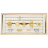 Display nero per anelli in legno con diversi anelli su sfondo beige