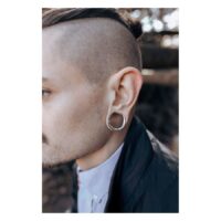 Uomo con Ear Saddles argentati nell'orecchio davanti a uno sfondo sfocato
