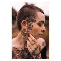 Persona con piercing Mandala Labret dorati e tatuaggi su viso e corpo