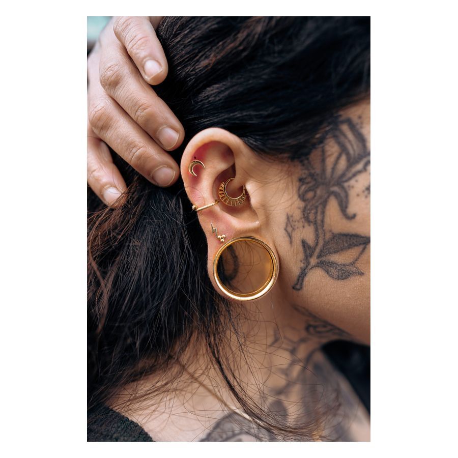 Persona con Triplet Barbell dorato e altri piercing nell'orecchio