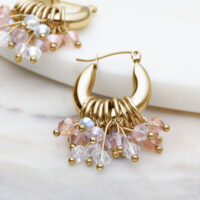 Orecchini Glamour Hoops dorati con cristalli colorati su sfondo chiaro