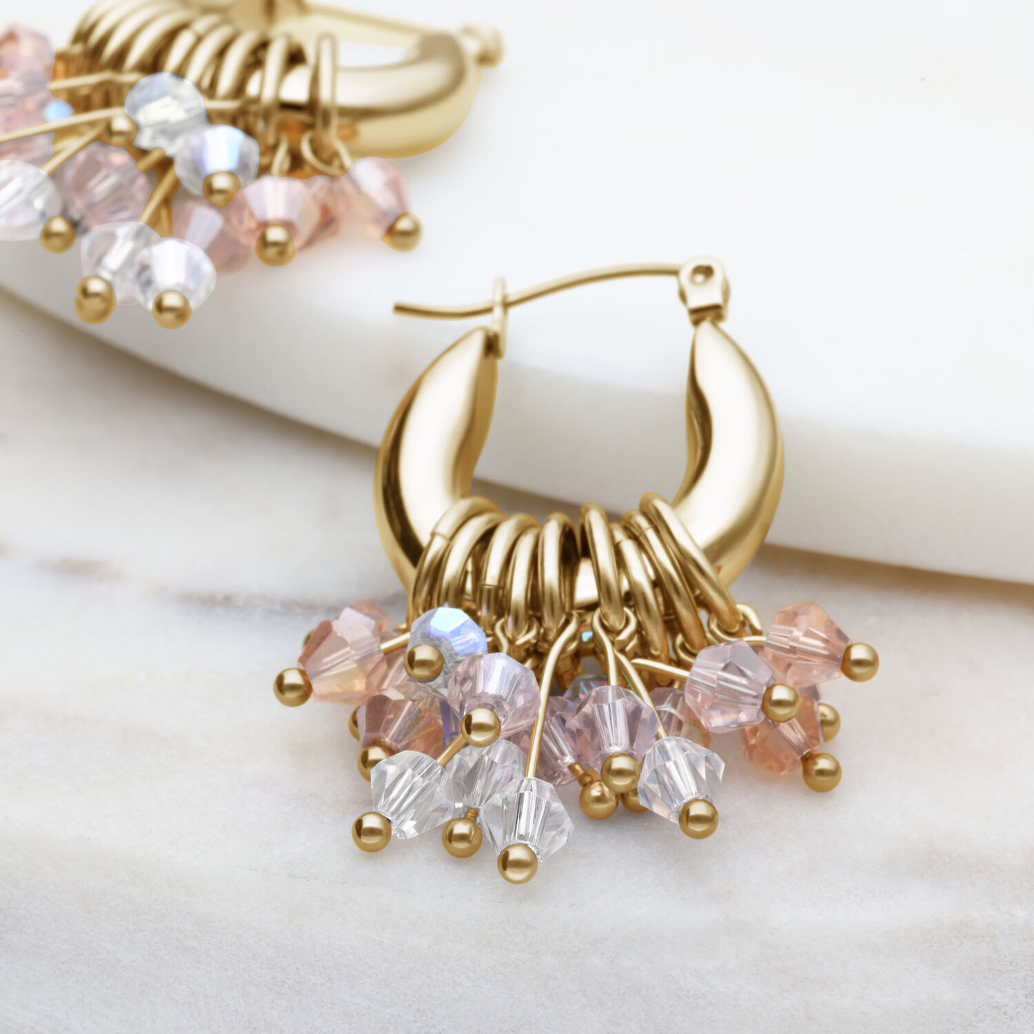 Orecchini Glamour Hoops dorati con cristalli colorati su sfondo chiaro