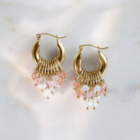 Orecchini Glamour Hoops dorati con cristalli rosa e chiari su sfondo di marmo